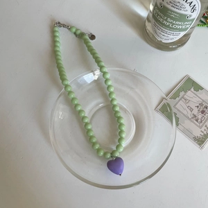 Détail du collier de perles vert menthe avec pendentif cœur violet et fermoir mousqueton