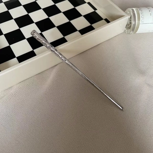 Detailed macro view of irregular hammer-texture silver hair pin on textured fabric
