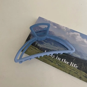 Matte finish gradient blue hair claw clip with triangular cutout design on a magazine