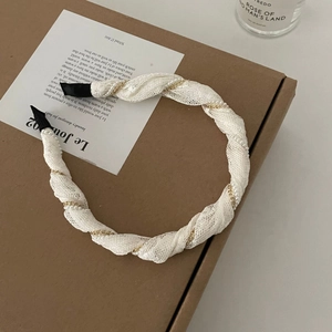 Détail d'un serre-tête en dentelle blanche avec chaîne dorée et perles