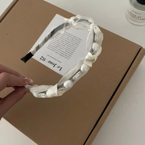 Détail du serre-tête en tulle blanc orné de perles élégantes sur un support noir