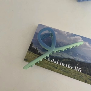 Close-up of large blue and green gradient shark clip with matte finish on aesthetic card