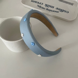 Close-up of light blue floral headband with 3D flower decorations on a white cup
