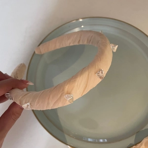 Elegante cerchietto in tessuto plissettato beige con decorazioni in cristallo per donna