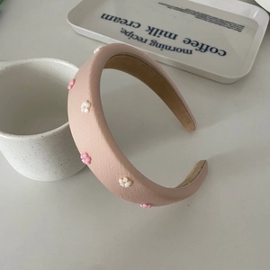 Chic padded headband with small floral accents in peach pink for a stylish hair accessory