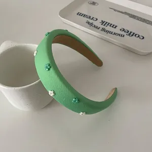 Detail of light green sponge headband with decorative 3D floral beads and textured fabric
