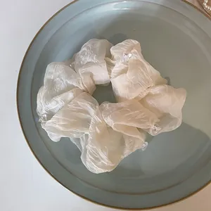 Vista macro di un elastico per capelli in tessuto a pieghe avorio con piccoli cristalli