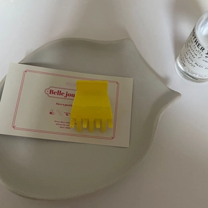 Détail d'une petite pince à cheveux jaune sur un plateau décoratif au style minimaliste