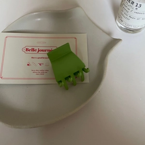 Vue détaillée de la petite pince à cheveux vert herbe mat sur une assiette décorative