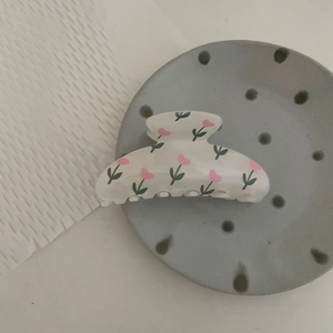 Detail view of cream flower hair claw clip with pink tulips on a decorative tray