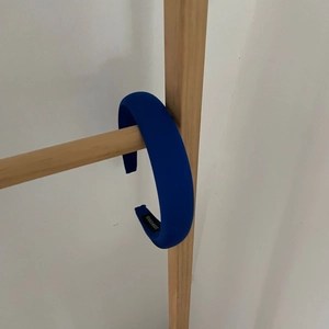 Detail view of deep blue padded sponge headband with HAND MADE label on wooden stand