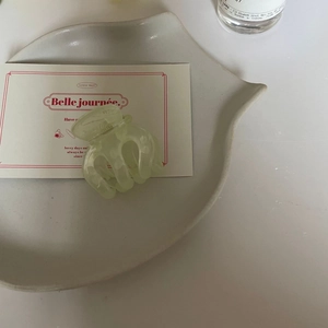 Détail d'une pince à cheveux vert clair translucide sur un plateau en céramique