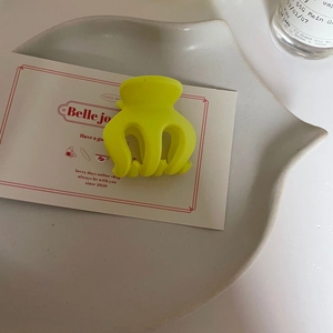 Vue détaillée de la pince à cheveux jaune fluo mate sur plateau en céramique décoré