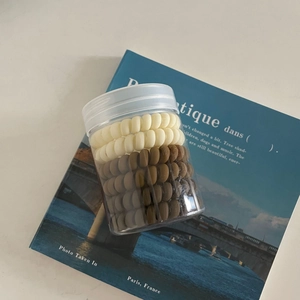 Élastiques à cheveux spirales crème et marron dans un pot en plastique transparent