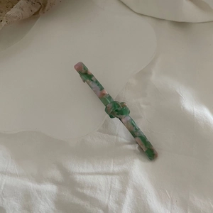 Detailed macro view of knotted acetate hair clip with green pink marble texture
