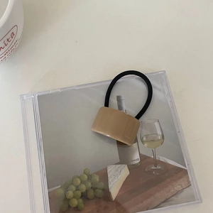 Élastique à cheveux minimaliste avec cube en acrylique beige sur un bureau blanc
