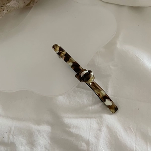Detail of tortoise shell acetate hair clip with knot design on white cloud background