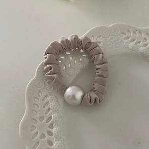 Chouchou élégant en satin lavande avec grande perle décorative dans un plateau en céramique