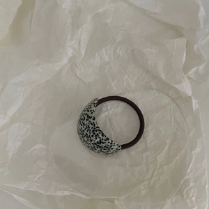 Détail d'un élastique à cheveux minimaliste avec charme en acétate à pois noir et blanc