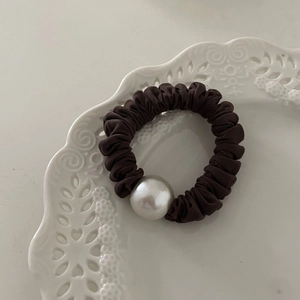 Chouchou en soie marron foncé avec grande perle dans une coupelle en dentelle fine
