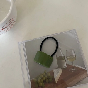 Vue détaillée d'un élastique à cheveux avec perle en acrylique vert herbe minimaliste