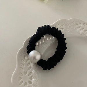 Vue détaillée d'un chouchou noir orné d'une grande perle blanche sur une assiette blanche