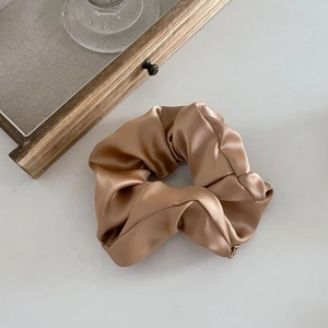 Gros plan d'un chouchou en satin doré champagne avec une texture de soie et des plis doux
