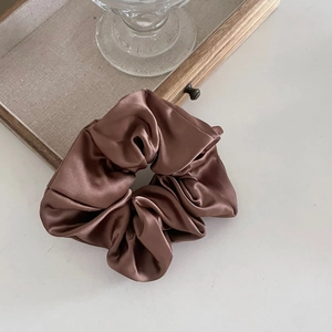 Gros plan d'un chouchou en satin soyeux marron thé au lait avec texture élégante