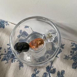 Retro-Haarspange aus Kristall-Acryl in Bonbonform in Glasschale auf Blumenhintergrund