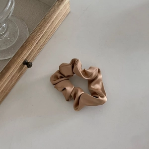 Détail d'un chouchou en satin doré champagne avec une texture lisse et un éclat soyeux