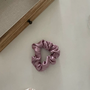 Vue détaillée du chouchou en satin lilas avec des plis élégants sur un plateau en bois