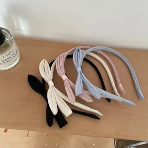Draufsicht auf fünf elegante Stoff-Haarreifen mit Schleifen in Pastellfarben auf Holz