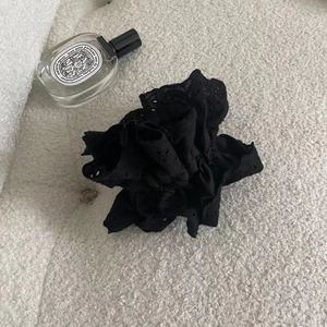 Detail of black cotton lace hair scrunchie with intricate embroidery and ruffled texture