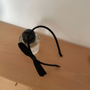 Detailaufnahme eines schwarzen Haarreifs mit seitlicher Schleife auf hellem Holz