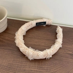 Elegant beige lace floral headband with handmade tag on a vintage wooden surface