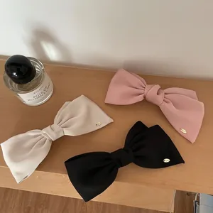 Three-piece set of large satin bow hair clips in cream, pink and black colors