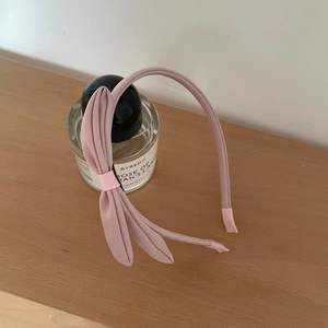 Detailansicht eines eleganten rosa Stoff-Haarreifens mit Schleife und gerippten Enden