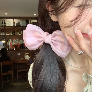 Pink satin bow hair clip for women, elegant oversized ribbon accessory on long hair