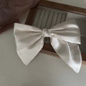 Elegant cream satin oversized bow hair clip with a silky glossy finish and vintage style