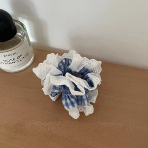 Detailansicht eines blau-weißen Karo-Haargummis mit weißem Blumen-Spitzenbesatz