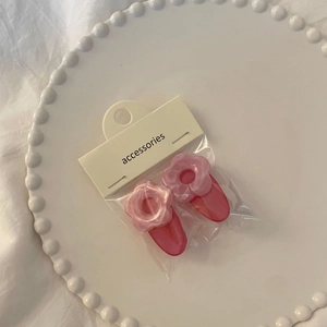 Close-up of pink jelly flower hair clips on an elegant white ceramic plate with beads
