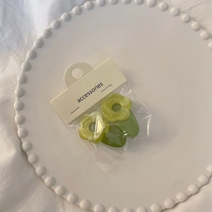 Close-up of translucent grass green flower hair clips on a white ceramic display plate