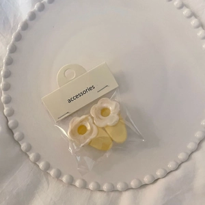 Pair of yellow jelly flower hair clips with white centers on display card in a tray