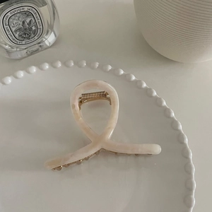 Petite pince à cheveux en acétate marbré beige sur un plateau en céramique