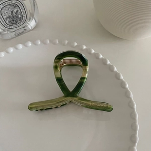 Pince à cheveux en acétate rétro français à texture marbrée verte sur assiette blanche