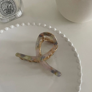 Gros plan sur la pince à cheveux en acétate marbré posée sur une assiette décorative