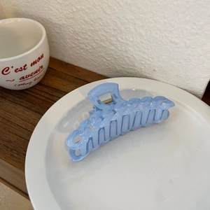 Pince à cheveux chaîne bleu translucide sur assiette blanche au style minimaliste français