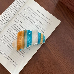Vue détaillée d'une pince à cheveux nuage en acétate avec rayures colorées et pailletées