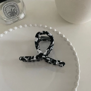 Détail d'une pince à cheveux en acétate marbré posée sur une assiette décorative en céramique