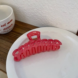 Détail macro d'une grande pince à cheveux rose translucide en chaîne sur assiette